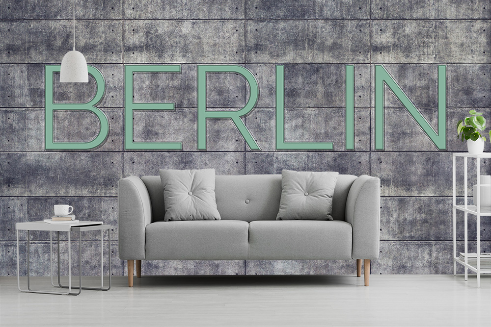 Papier peint photo - Salon élégant avec canapé gris devant un mur en béton avec l'inscription Berlin