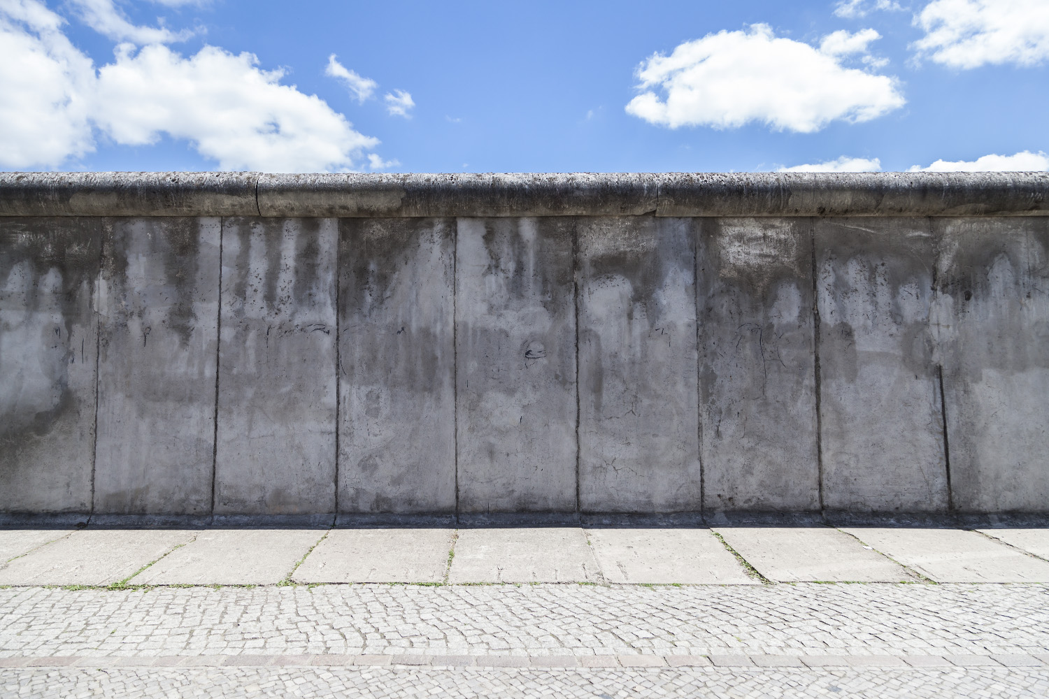 Papier peint photo - Détail d'un vieux mur en béton sous un ciel bleu avec des nuages blancs