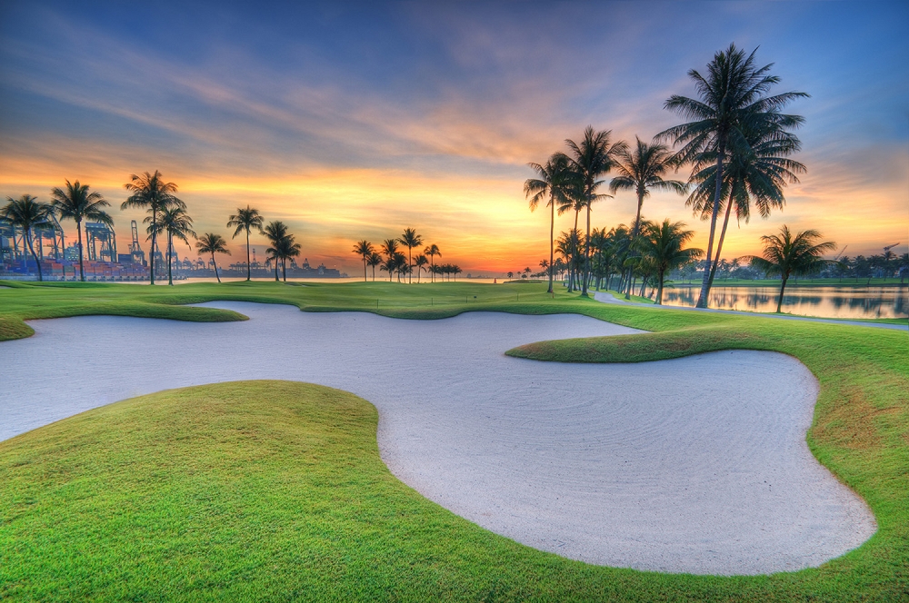 Papier peint photo - Vue pittoresque d'un terrain de golf au lever du soleil avec des palmiers et des bunkers de sable