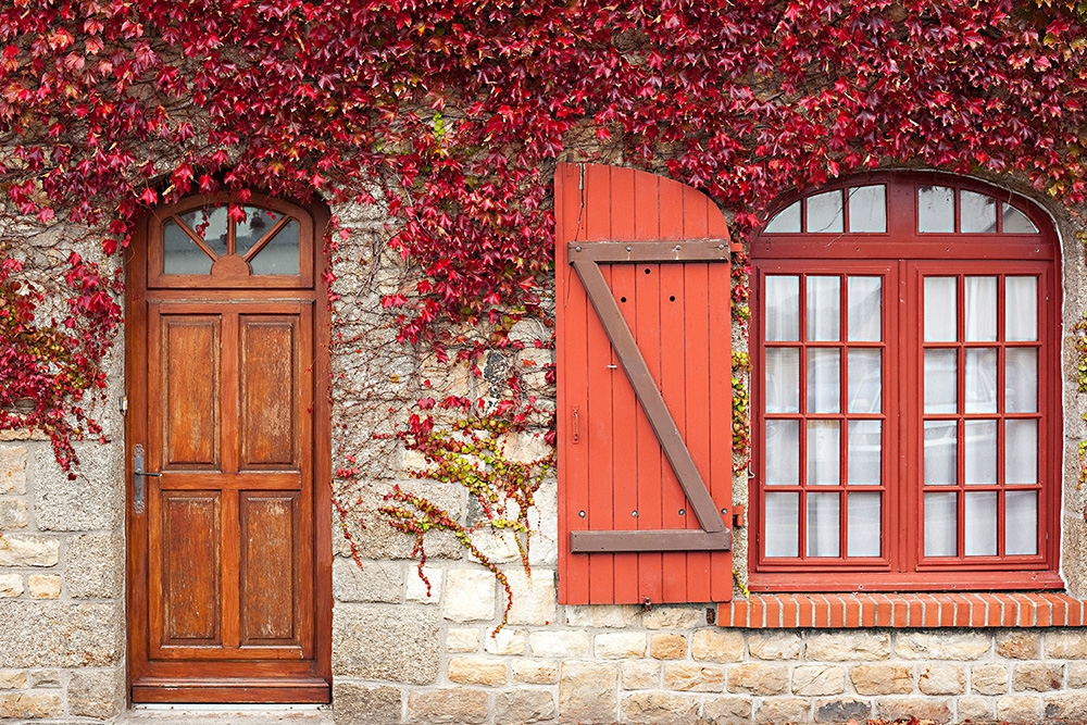 Papier peint photo - Maison rustique en pierre avec porte en bois, volet rouge et lierre