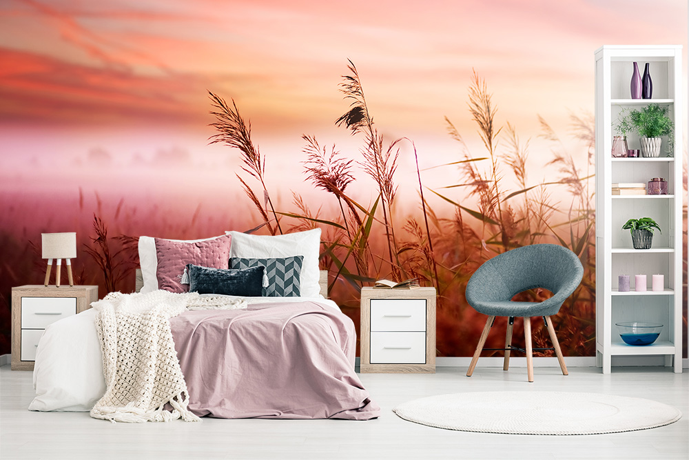 Papier peint photo - chambre à coucher avec des draps pastel et une décoration murale avec un lever de soleil sur un champ d'herbe