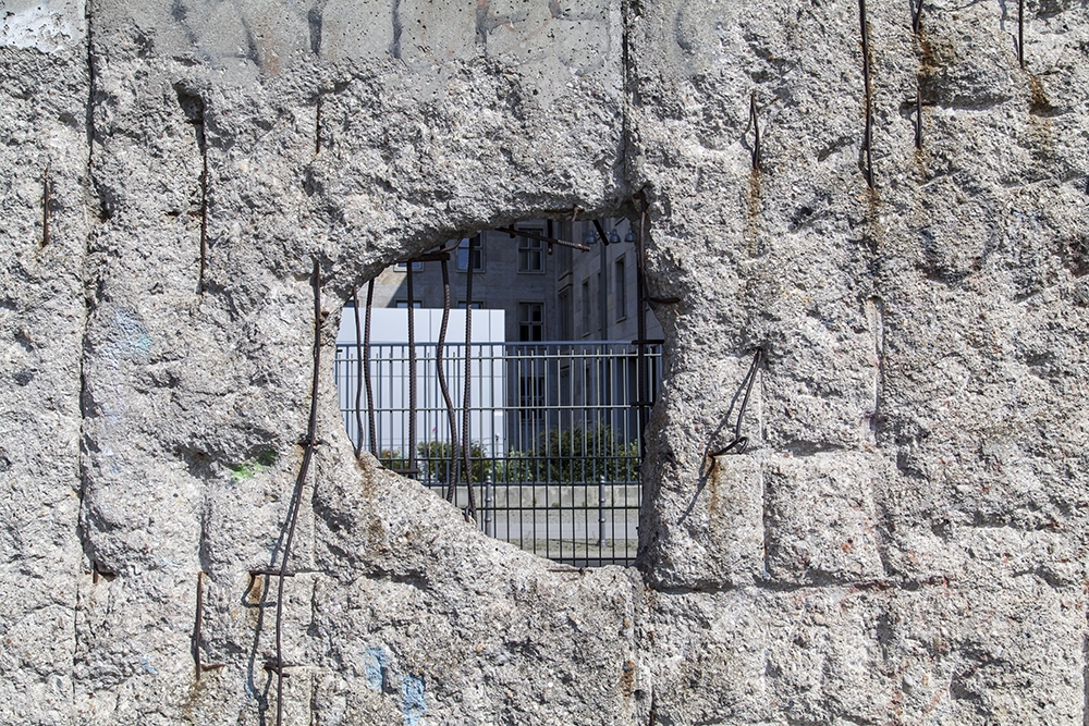 Papier peint photo - trou dans le mur de Berlin avec vue sur les bâtiments de la ville situés derrière